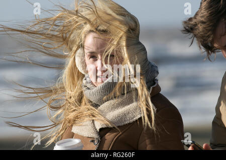 Blackpool, Lancashire. 27 Jan, 2019. UK Wetter. Gale force Winde an der Küste. Die Besucher der Stadt am Meer haben strenge Winde mit Fußgängern auf der Strandpromenade ausgeblasen wird zu ertragen. Sturm, Schlag, tempest, Flyaway Haar, verwirrte Tresses, Bad Hair Day auf der Strandpromenade. Credit: MediaWorldImages/AlamyLiveNews Stockfoto