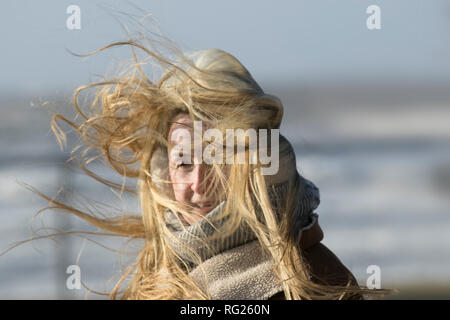 Blackpool, Lancashire. 27 Jan, 2019. UK Wetter. Gale force Winde an der Küste. Die Besucher der Stadt am Meer haben strenge Winde mit Fußgängern auf der Strandpromenade ausgeblasen wird zu ertragen. Sturm, Schlag, tempest, Flyaway Haar, verwirrte Tresses, Bad Hair Day auf der Strandpromenade. Credit: MediaWorldImages/AlamyLiveNews Stockfoto