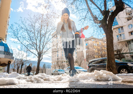 Frau zu Fuß durch die Schneeschmelze im späten Winter Stockfoto