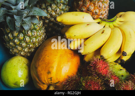 Ananas, Bananen und Rambutan Exotische noch Leben. Tropische Frucht Haufen Eingestellt von Oben nach Unten Detailansicht. Reisen zu den lokalen Thailand Lebensmittelmarkt für Frische Orga Stockfoto