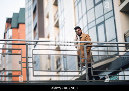 Attraktive indischer Geschäftsmann auf Bürgersteig und spricht über sein Smartphone. Stockfoto