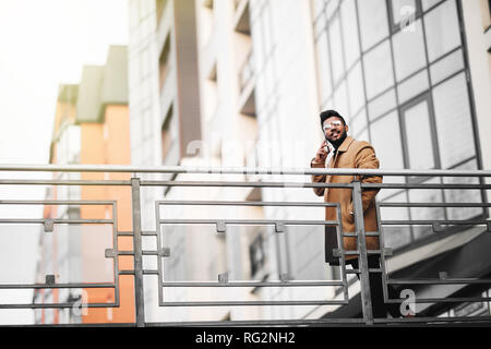 Junge indische Geschäftsmann am Telefon zu sprechen in der Stadt, vor modernes Gebäude. Stockfoto