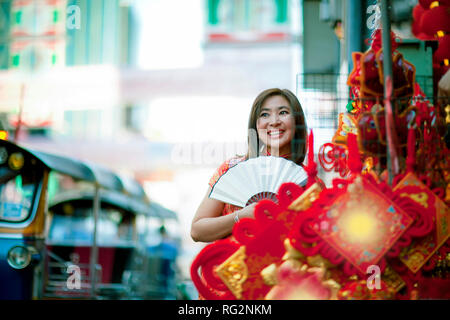 Asiatische Frau mit der chinesischen Tradition Kleidung mit chinesischen Bambus Ventilator toothy Lächeln in yaowarat street Chinatown von Bangkok Thailand Stockfoto