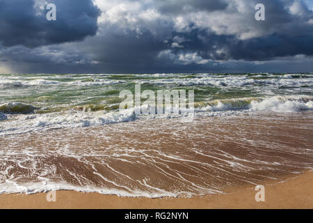 Blick vom Strand auf schwere, dunkle Regenwolken über dem stürmischen Meer. Stockfoto