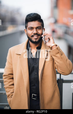 Portrait von bärtigen indischen Mann im Mantel, am Telefon zu sprechen auf der Straße Stockfoto
