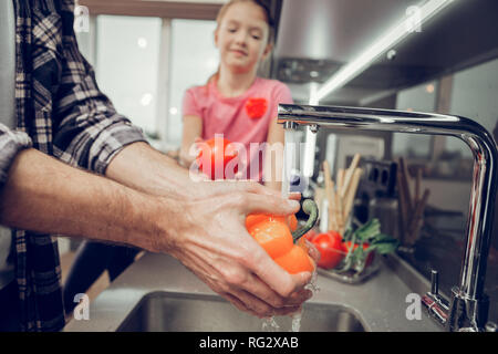 Mann in einem kariertem Hemd waschen Gemüse vor dem Frühstück Stockfoto