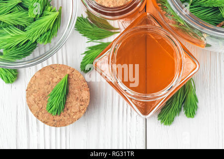 Hausgemachte kiefer Hustensirup für trockene reizt Kehle hustet. Von Grün jungen Kiefer Knospen und Honig. Alternative Medizin Konzept auf weißem Holz- Registerkarte Stockfoto