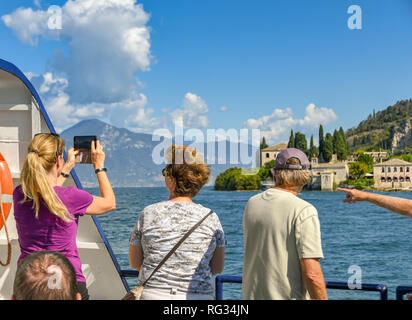 Gardasee, Italien - September 2018: Leute, die aus einer Fähre am Gardasee. Eine Person ist, die ein Bild auf einem Mobiltelefon. Stockfoto