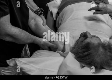 Der physiotherapeut Riccardo Di Lauro arbeiten an einer reifen Frau, die eine Narbe auf Ihrer linken Schulter, der lag auf einem Bett im Krankenhaus Stockfoto
