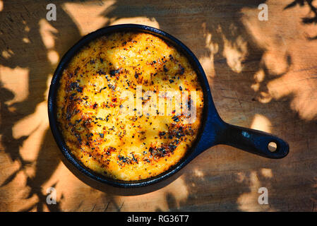 Köstlichen argentinischen Provolone Garn Käse (Provoleta), die in einer gusseisernen Pfanne über der Glut auf einem alten Holz- Board vorgestellt gekocht wurde. Stockfoto