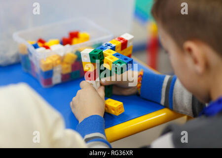 In der Nähe der Hände Kind spielen mit bunten Kunststoff Ziegel am Tisch. Die ersten Schritte für die Entwicklung der technischen Art des Denkens. Stockfoto