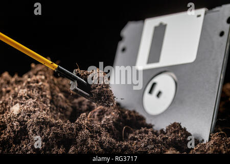 Die Diskette ist halb in die Erde eingegraben, neben einer Schaufel Stockfoto