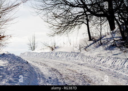 Weiß verschneite Straße und schwarze Äste Stockfoto