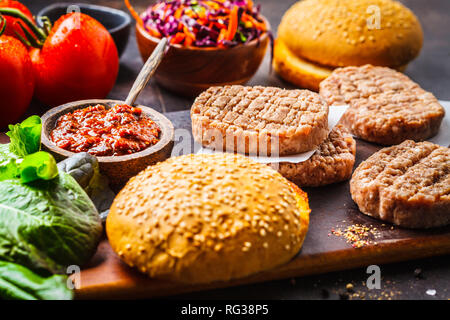 Zutaten für Fleisch Burger mit Gemüse und Krautsalat auf einem dunklen Hintergrund, Ansicht von oben, kopieren. Stockfoto