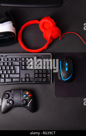 Ansicht von oben ein Gaming Gear, Maus, Tastatur, Joystick, Headset, VR-Headset auf Schwarz tisch Hintergrund. Gamer Arbeitsbereich Konzept. Stockfoto