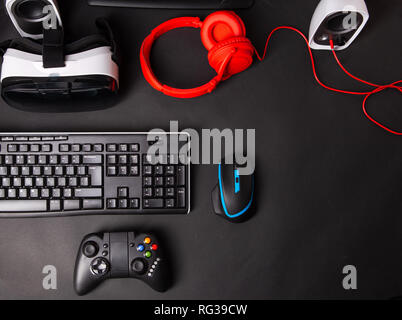 Ansicht von oben ein Gaming Gear, Maus, Tastatur, Joystick, Headset, VR-Headset auf Schwarz tisch Hintergrund. Gamer Arbeitsbereich Konzept. Stockfoto