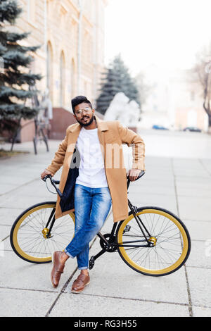 Portrait von indischen Hipster bärtiger Mann mit dem braunen Haar zu Fuß mit dem Fahrrad auf der Straße Stockfoto