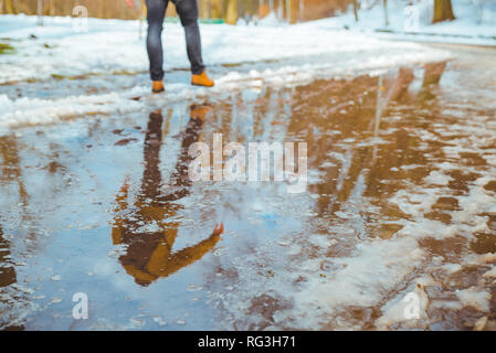 Schmelzender Schnee. große Pfütze. Mann, der versucht, durch. Der Frühling kommt Stockfoto