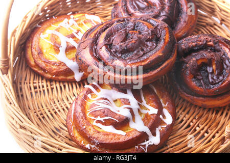 Frisch gebackene hausgemachten süßen Brötchen oder süße Brötchen mit Zimt in einem Weidenkorb. Stockfoto