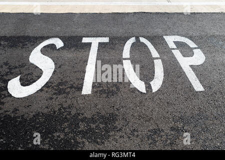 Stop, auf einem schwarzen Asphaltstraße gemalt. Stockfoto