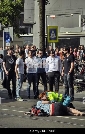 Blick auf eine junge Frau, die auf die Straßenbahnschienen nach einem Unfall auf der Bilderdijkstraat gelangen, durch die Passanten und Ambulance Service Menschen umgeben. Stockfoto