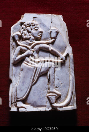 Männliche Figur & Papyrus: Nimrud Ivory von Zimmer SW 37 Fort Salmanassar innerhalb des assyrischen Stadt Nimrud, Nordirak, fotografiert in Bristol Museum. Stockfoto