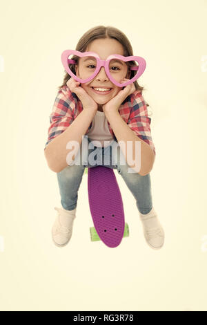 Kind in Herzform Brillen mag Skateboarding. Fröhlich und glücklich. Kind Mädchen lässigen Stil mit Penny board genießen Kindheit. Mädchen fröhlich glücklich mit Skateboard isoliert weiß. Hobby Freizeit Konzept. Stockfoto