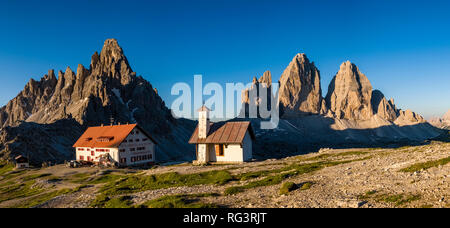 Panoramablick auf den Berg Gruppe Tre Cime di Lavaredo und Paternkofel, Monte Paterno, bei Sonnenaufgang, mit der Berghütte Dreizinnenhütte und eine kleine Stockfoto