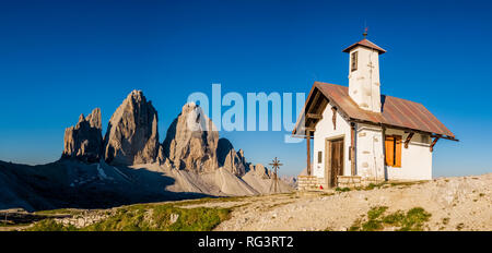 Panoramablick auf den Berg Gruppe Tre Cime di Lavaredo, mit einer kleinen Kapelle neben der Berghütte Dreizinnenhütte Stockfoto