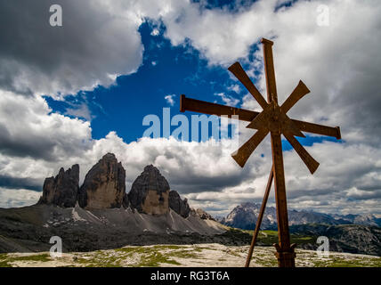 Panoramablick auf den Berg Gruppe Tre Cime di Lavaredo, mit Metall kreuz und dunklen Gewitterwolken anfahren Stockfoto