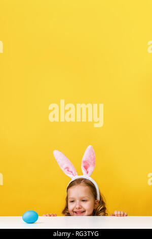 Süßes kleines Kind Mädchen mit Hasenohren zu Hause ist die Jagd für Ostern Eier. Stockfoto