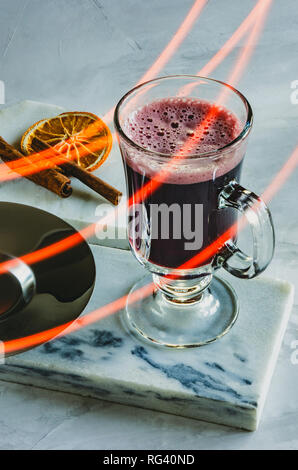 Glas Becher Glühwein auf Marmor, getrocknete Orangen und Zimt Stockfoto