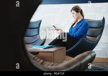 Serious Business Frau mit Smartphone im Büro Wartezimmer Stockfoto