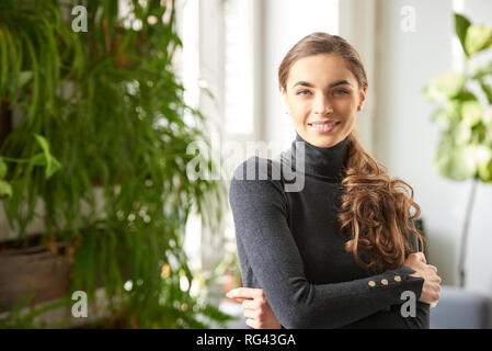 Nahaufnahme Porträt der schönen jungen Frau mit Rollkragen Pullover bei Kamera suchen und lächelnd Indoor. Stockfoto