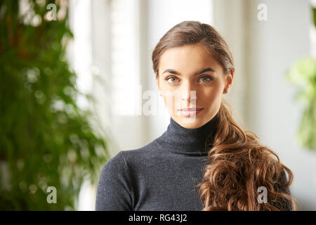 Nahaufnahme Porträt der Schönen lächelnden jungen Frau tragen rollkragen pullover bei Kamera suchen und lächelnd Indoor. Stockfoto