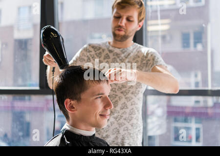 Professionelle Friseursalons. Schuss ein Friseur trocknen die Haare mit Fön von man-Client Stockfoto