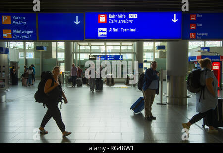 FRANKFURT AM MAIN, Deutschland - 29 AUGUST 2018: Personen mit Gepäck verlassen den Flughafen Frankfurt, Info Board mit Richtung Schilder über, Frankfurt/Main, Stockfoto