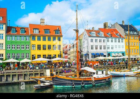 Malerische Nyhavn Ansicht mit Booten durch die Böschung im hellen Sonnenschein, Menschen zu Fuß und Sitzen in Restaurants, Kopenhagen, Dänemark Stockfoto