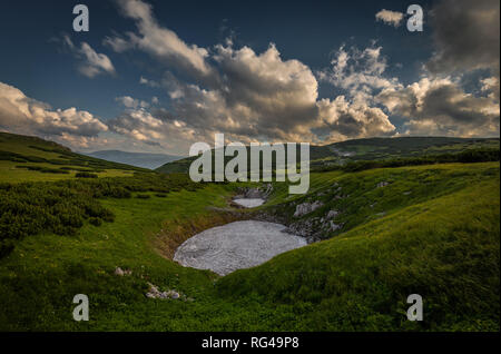 Kleiner Patch von Schnee im Sommer mitten in der grünen Wiese in rax Hochebene, in der Nähe der Route Dambocksteig aus Schneeberg, Österreich Stockfoto