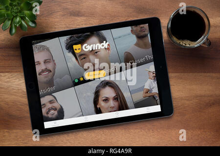 Die Website von grindr ist auf einem iPad Tablet gesehen, auf einer hölzernen Tisch zusammen mit einem Espresso und einem Haus Anlage (nur redaktionelle Nutzung). Stockfoto