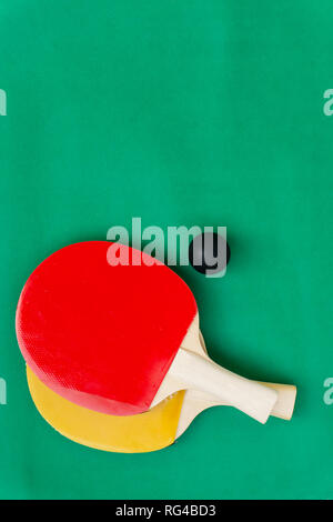 Rote und gelbe Tischtennisschläger mit schwarzen Bälle, Tischtennis Schläger und Bälle auf dem Tisch. Stockfoto