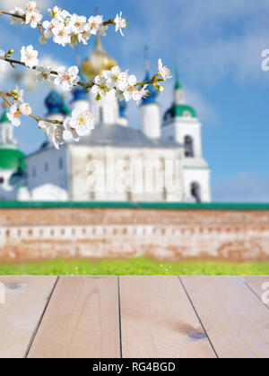 Russisch-orthodoxe Ostern verschwommenes Gebäude der Kirche helle, sonnige Hintergrund. Rustikale Holzplanken Tabelle mockup. Spring Blossom. Cherry Tree Branch mit Wh Stockfoto