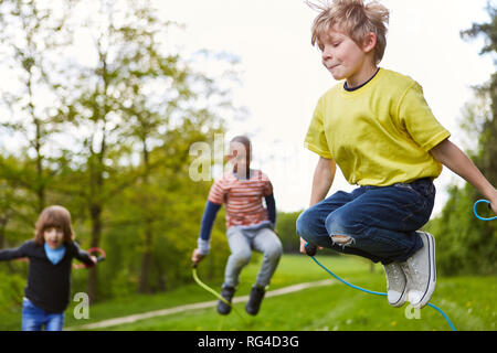 Junge im Park zusammen mit Freunden in den Wettbewerb im Rope Skipping im Sommer Stockfoto