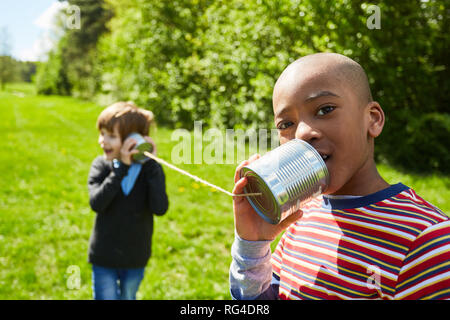 Afrikanischen jungen spricht in einem können Telefon mit Schnur in der Sonne im Park Stockfoto