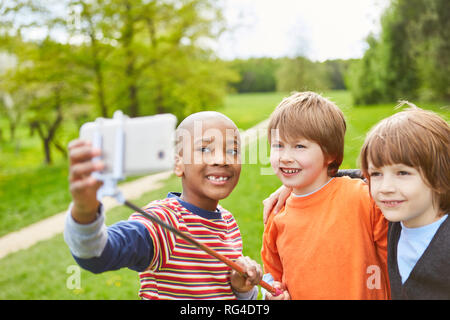 Drei Jungen nehmen ein selfie mit dem Smartphone auf selfie Stick im Park im Sommer Stockfoto