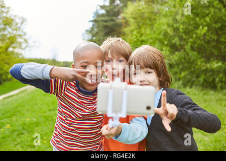 Drei Kinder gehen Nüsse und eine selfie mit Ihrem Smartphone auf dem selfie Stick nehmen Stockfoto