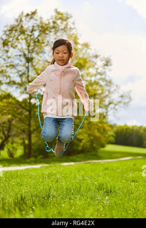 Asiatische Mädchen im Seil springen während der Ferien im Sommer Wiese Stockfoto