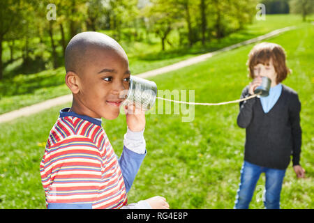 Zwei Kinder benutzen Sie das Telefon am Telefon während ihrer Sommerferien im Park Stockfoto