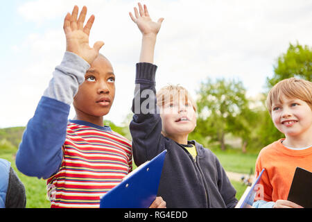 Kinder als Schüler im Biologieunterricht in der Natur beantworten Fragen in einer Untersuchung Stockfoto