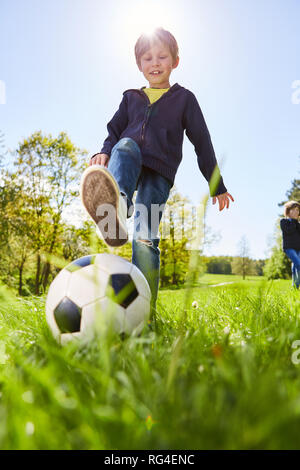 Junge spielt mit einem Fußball auf einer Wiese im Sommer Camp im Sommer Stockfoto